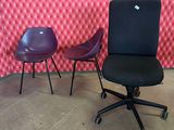 purple chairs and a black chair in front of a pink wall