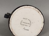 une vieille tasse en noir et blanc, sur laquelle figurent des inscriptions, posée sur une table