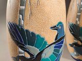 two vases with birds painted on them sitting on a table