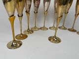 six gold wine glasses lined up in a row on a white surface