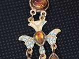 a close up of a silver and gold pendant with a bird on it