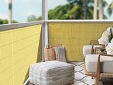 a chair and ottoman on a balcony with a yellow wall
