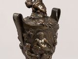 a bronze statue of a boy sitting on a vase