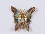 a blue and gold butterfly brooch on a white surface