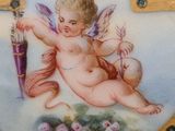 a blue and gold plate with a picture of a cupid on it