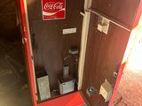 a coca cola machine in the corner of a room