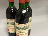 three bottles of red wine sitting on top of a white table