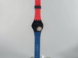 a red and blue watch sitting on top of a glass