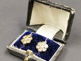 une photo représentant une paire de boucles d'oreilles dans une boîte posée sur une table