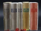 four books are lined up in a row on a black surface