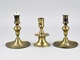 three brass candlesticks on a white surface with a white background