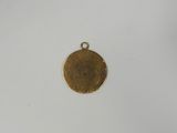 a close up of a gold plated pendant on a white surface