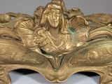 a gold sculpture of a woman sitting on a leaf