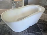une grande baignoire blanche posée sur un tapis dans une salle de bains