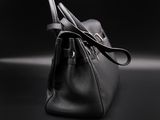 a black purse sitting on top of a table next to a black wall