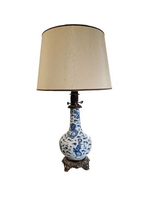 a blue and white vase with a lamp on it