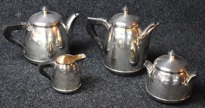 three silver teapots and two silver cups on a black surface