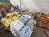 bags of food are stacked on pallets in a greenhouse