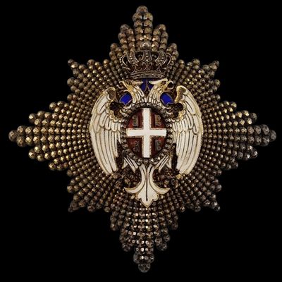 une croix en or surmontée d'une couronne et de deux ailes