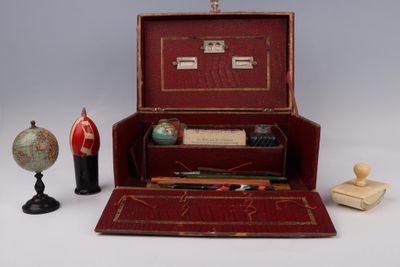 une valise rouge contenant un stylo, un globe terrestre et d'autres objets
