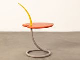 an orange side table with a curved top on a concrete floor