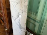 un socle en marbre dans un coin de la pièce, près d'une porte