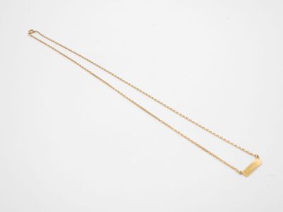 un collier en or composé d'une barre suspendue à une chaîne