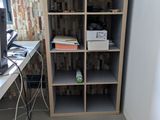 a book shelf in the corner of a room with a computer on it
