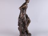 an antique bronze statue of a woman sitting on a rock