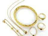 une photo représentant une collection de bijoux en or posés sur une surface blanche