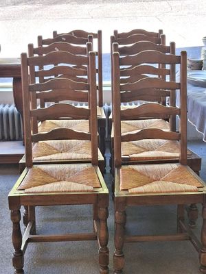 quatre chaises en bois disposées les unes à côté des autres sur un sol recouvert de moquette