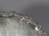 an antique silver tray with a decorative edge on a table