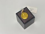 une petite pièce d'or dans une boîte noire posée sur une surface blanche