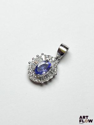 un gros plan d'un pendentif en forme de diamant bleu et blanc posé sur une surface blanche