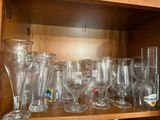 a wooden shelf filled with many glasses and vases