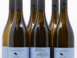 six bouteilles de vin sont alignées sur une surface blanche