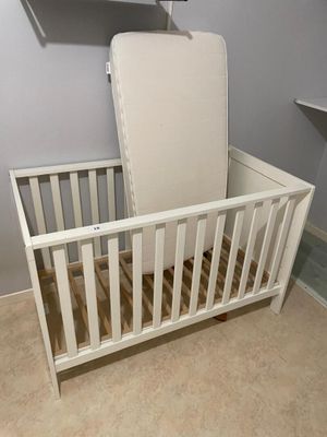 a white crib with a mattress on top of it
