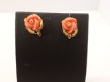 une paire de boucles d'oreilles couleur corail posées sur un présentoir noir