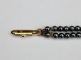 a close up of a black beaded bracelet with a gold clasp