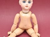 a wooden doll sitting on the floor with a red background