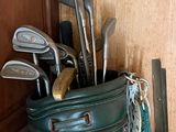 a green bag with golf clubs in it next to a door