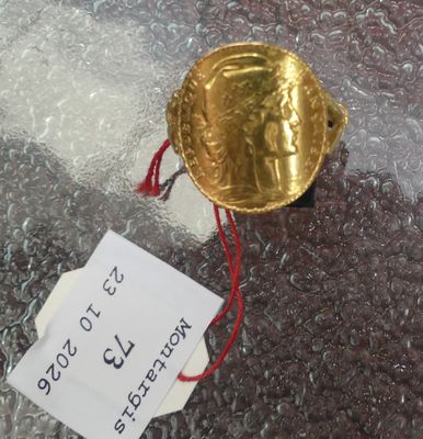 une pièce d'or posée sur un sac en plastique sur lequel est accrochée une étiquette de prix