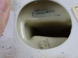 a hand holding a white porcelain vase with a label on it