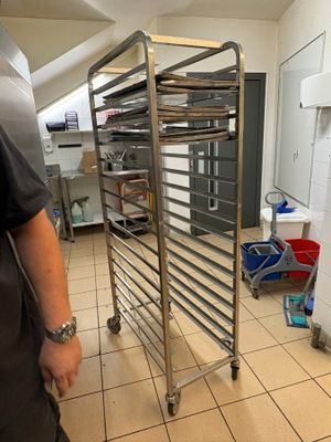 a man that is standing in a kitchen with a rack of food