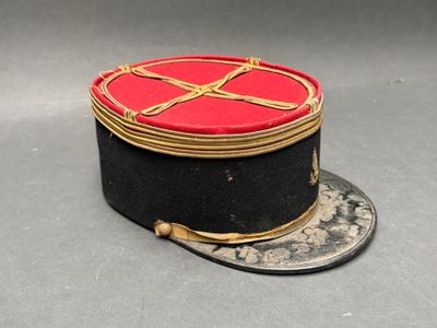 un chapeau rouge et noir orné d'un ruban doré
