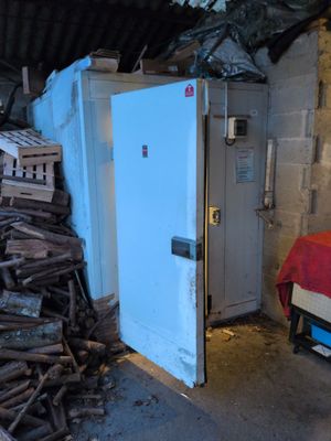a pile of wood next to a white refrigerator in a room