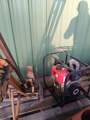 un homme debout à côté d'un tas de bois, avec un petit moteur