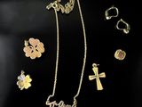 a collection of gold and silver jewelry including a cross, a flower, and a cross