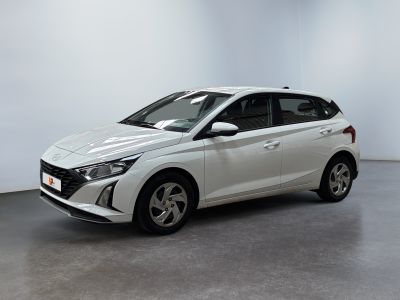 Une voiture blanche est garée dans une pièce aux murs blancs.