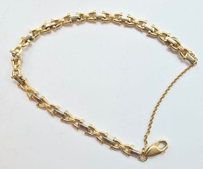 gros plan d'un bracelet en chaîne en or sur une surface blanche